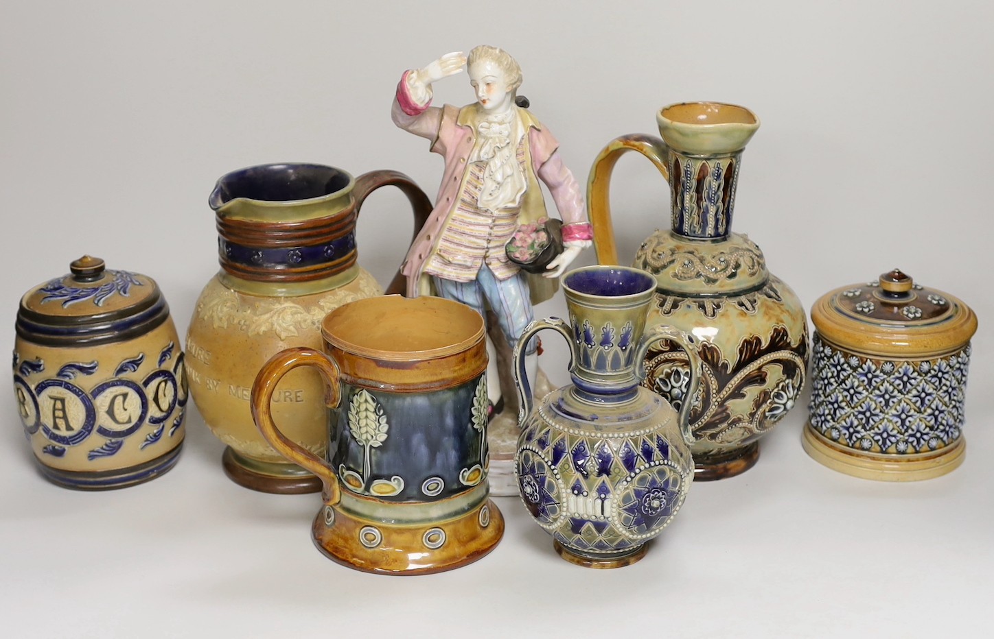 A group of six Doulton Lambeth stoneware vessels, tallest 22.5 cm and a French porcelain figure of a gentleman (7)